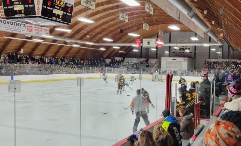 An overview of Roseau Memorial Arena featuring fans watching a high school hockey game.