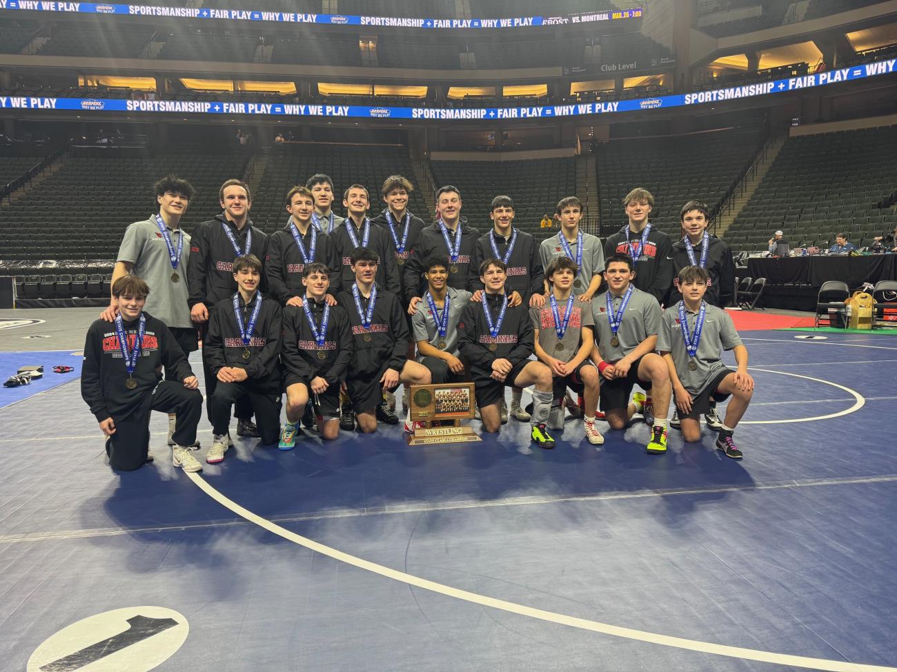 The Staples-Motley Wrestling team poses with its 2025 state championship trophy.