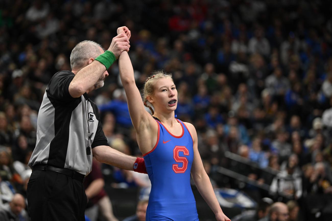 Simley's Charli Raymond's hand is raised after a wrestling victory.